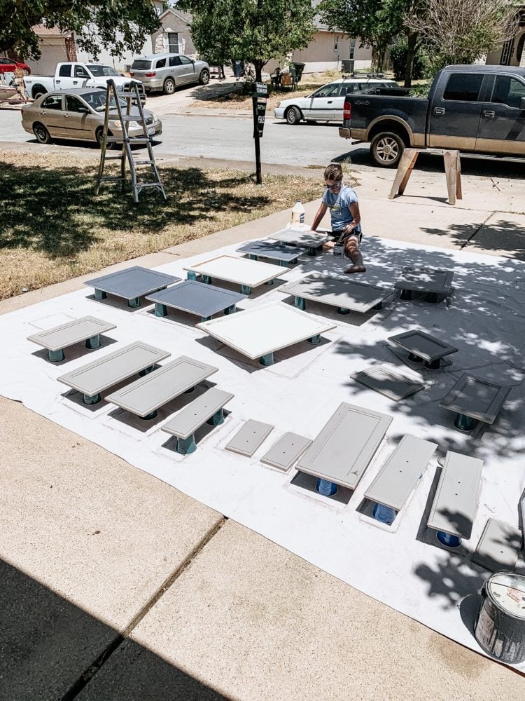 woman in a driveway painting cabinet doors