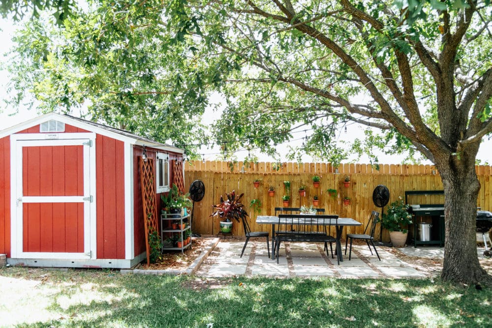 back yard with a red shed a pea gravel and paver patio