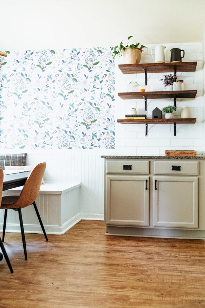 a kitchen and dining room with wallpaper, open shelving, and beige cabinets