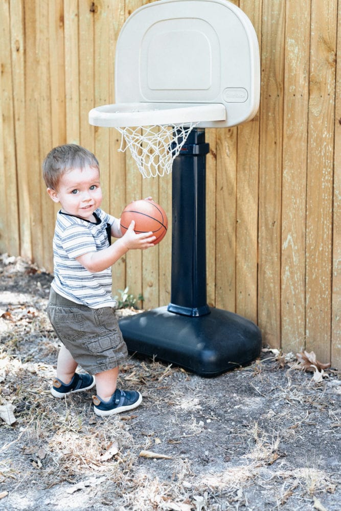 toddler playing with a little tikes basketball hoop