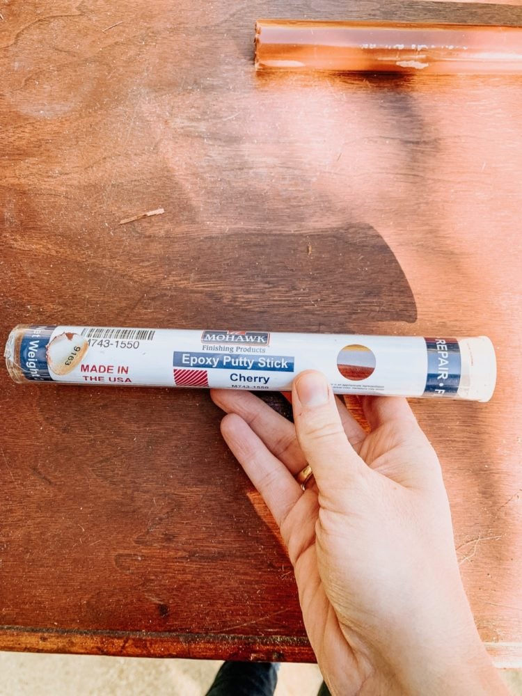 Close up of a woman's hand holding a Mohawk Epoxy Putty Stick 