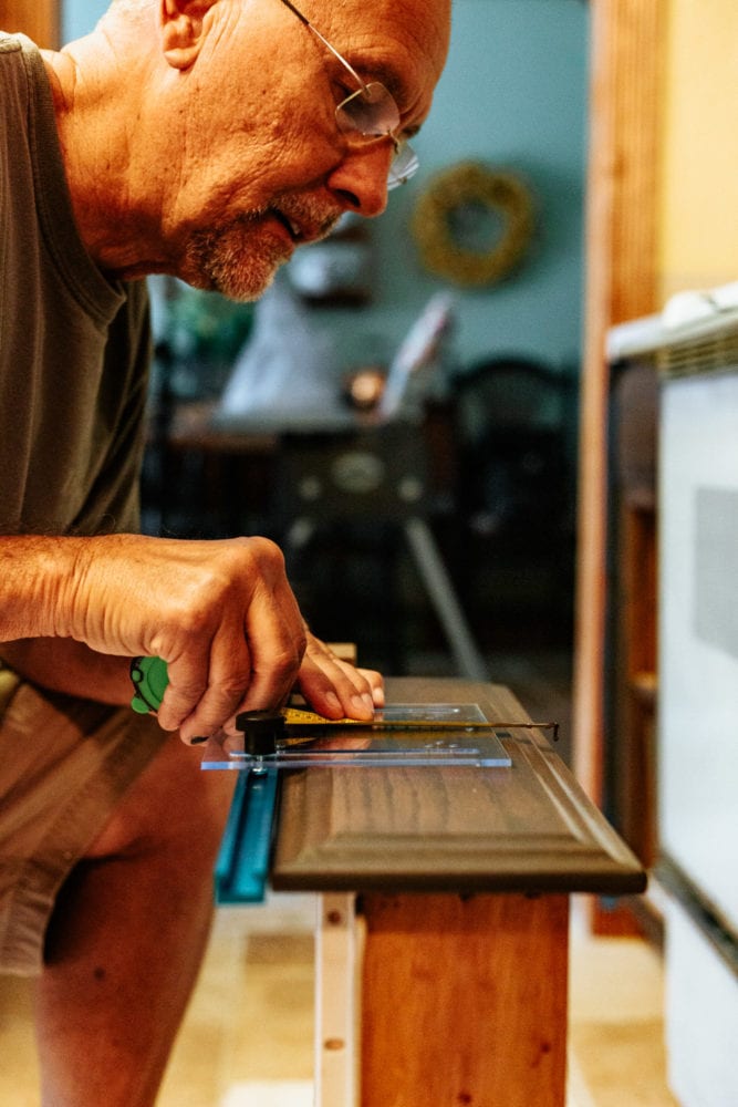 man measuring a drawer to install a drawer pull using a jig