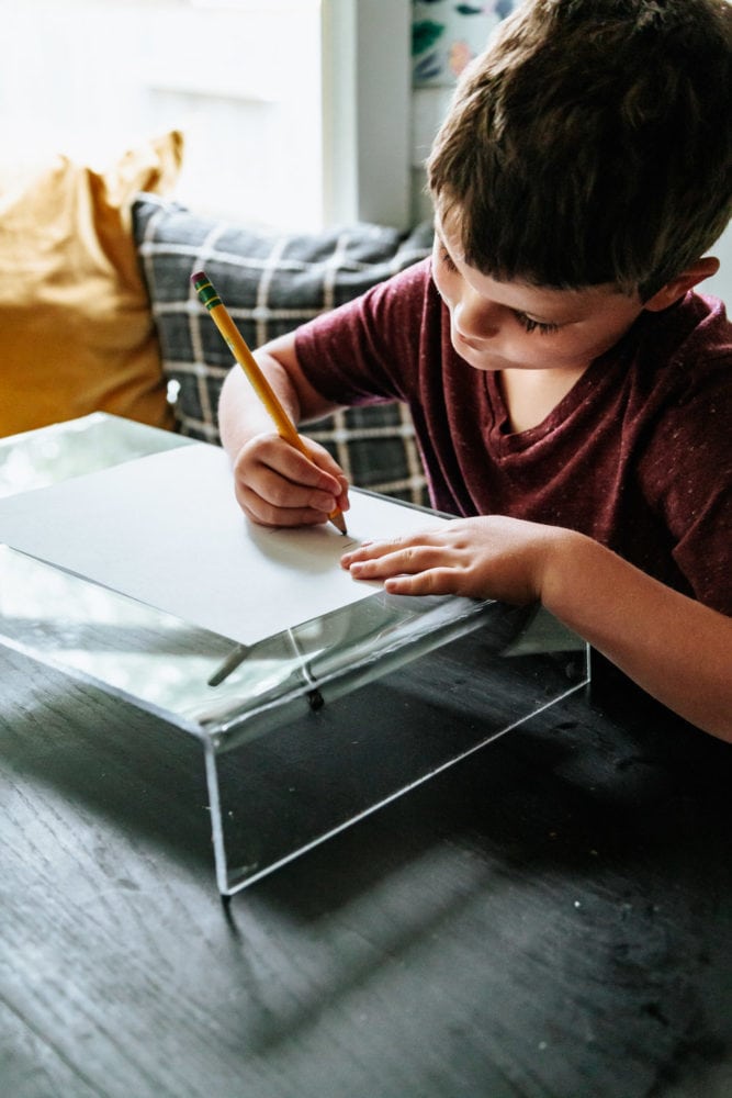 close up of a young boy coloring on an acrylic lap desk