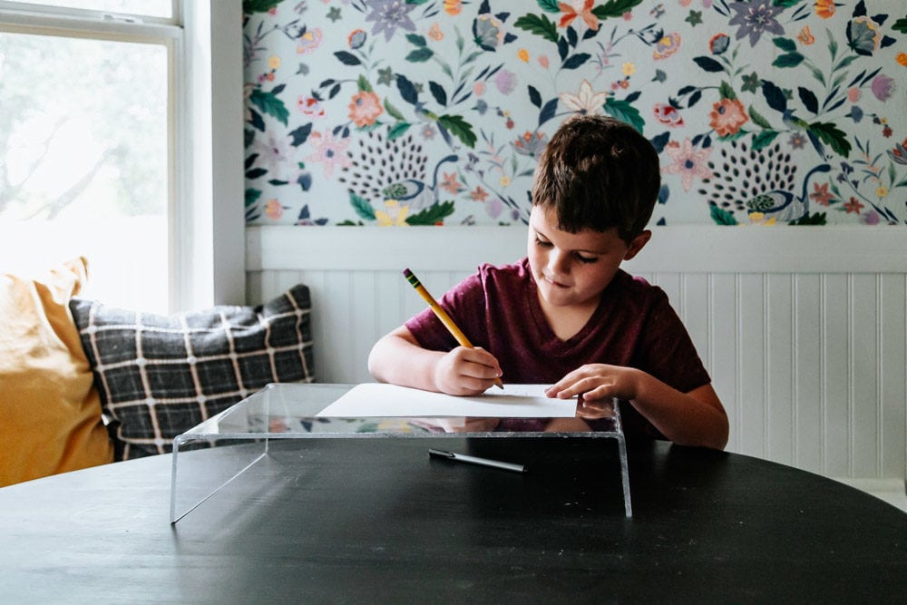 young boy drawing a picture on an acrylic lap desk