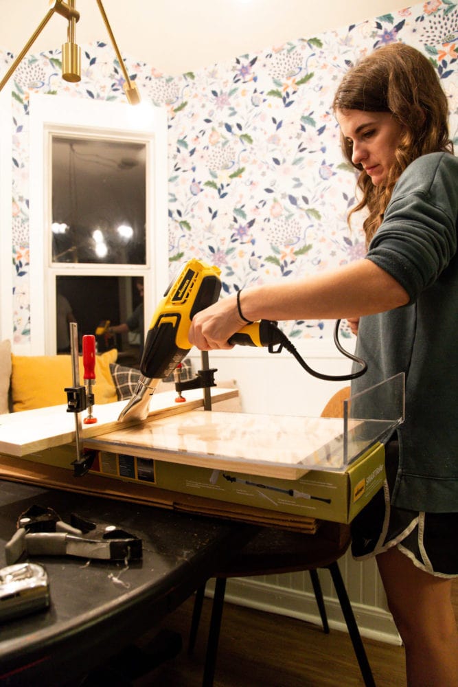 woman applying heat to plexiglass using a heat gun