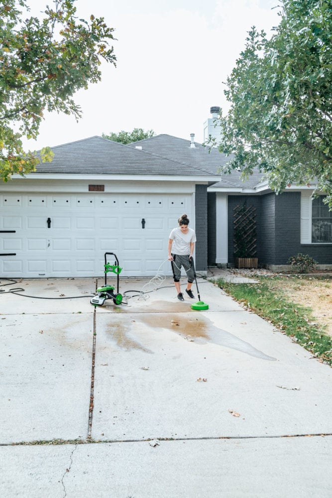 woman pressure washing a driveawy