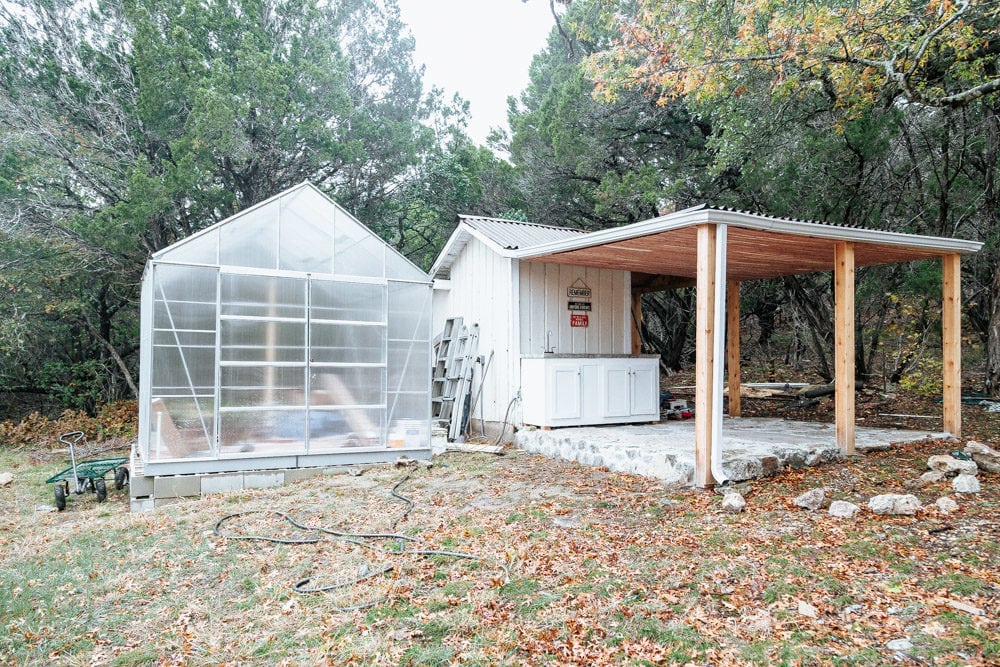 outdoor cedar-lined pergola next to a large greenhouse