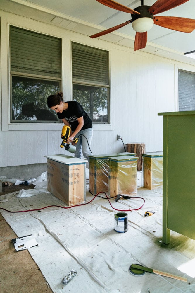 woman using a paint sprayer to paint a dresser 