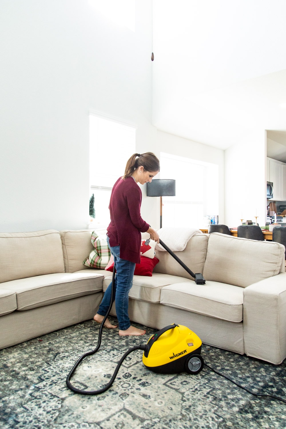 woman cleaning a sofa using a steamer 