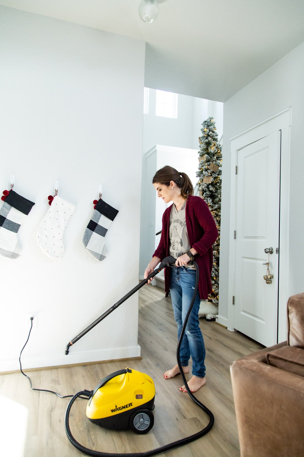 woman cleaning baseboards using a steamer