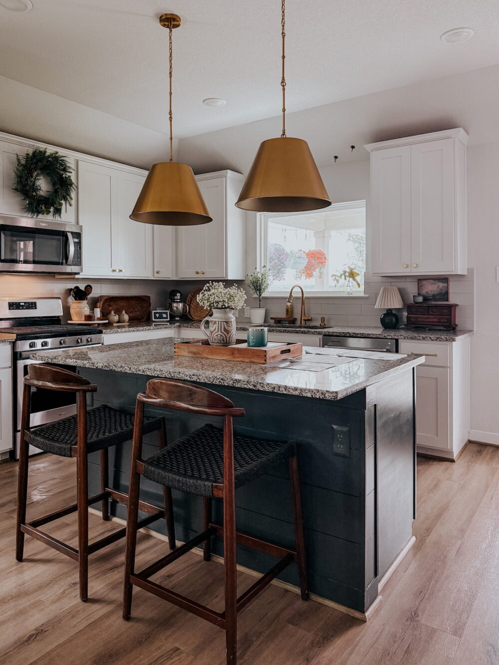 kitchen island with black paint, shiplap, and large gold pendants above it