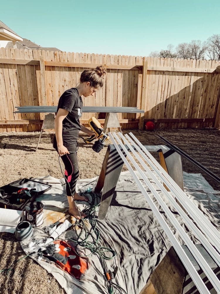 woman using a sprayer to paint trim