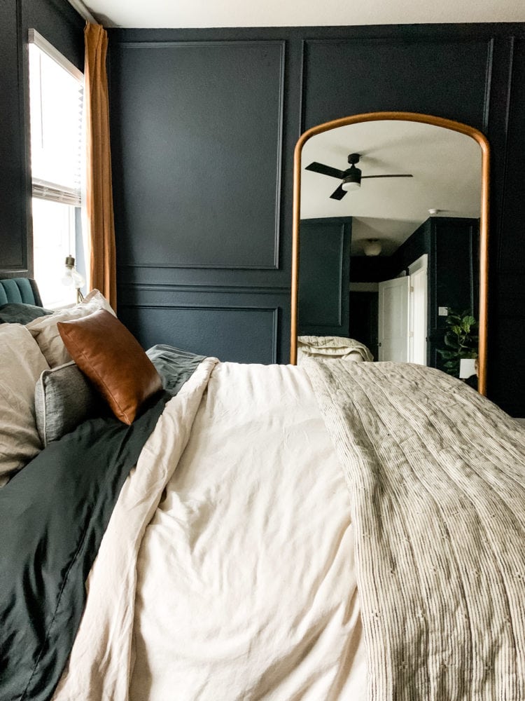 dark blue bedroom with a large mirror and gold curtains