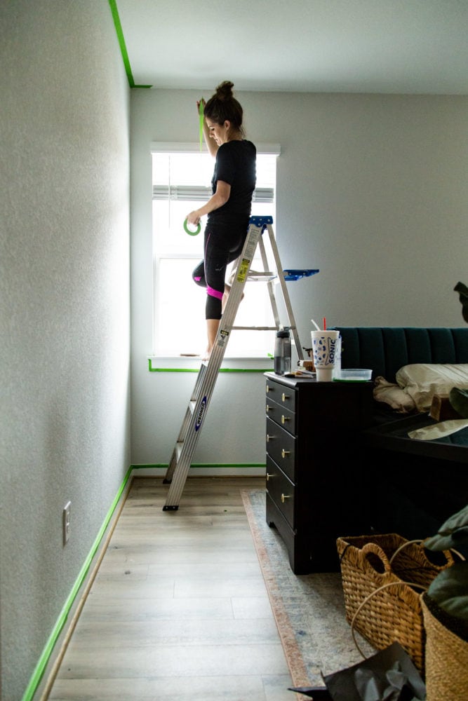 woman using painter's tape to prep for painting a room