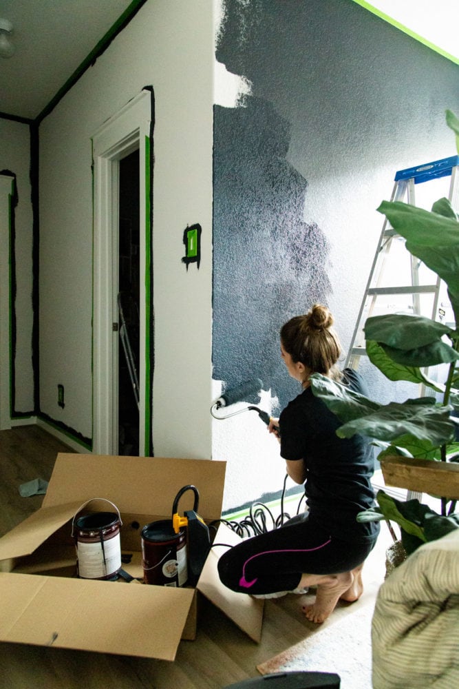 woman painting a wall dark blue