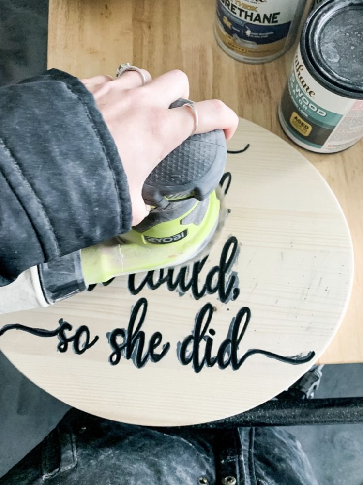 woman's hand sanding a wood carved sign