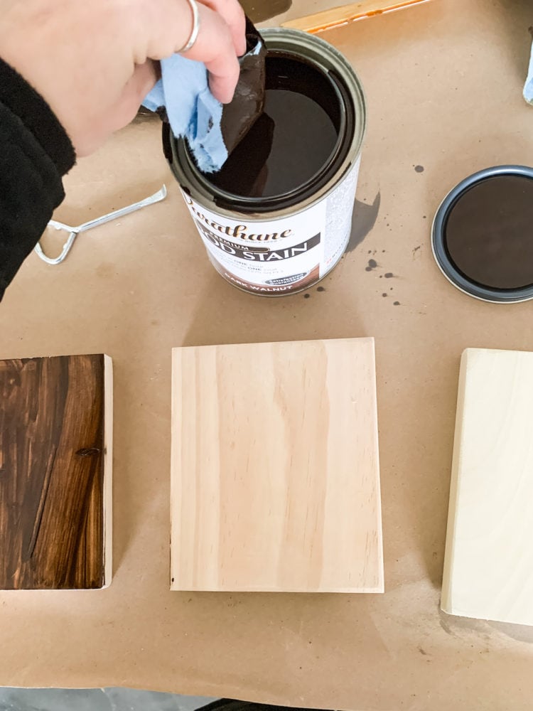 woman's hand staining a piece of wood with Varathane stain