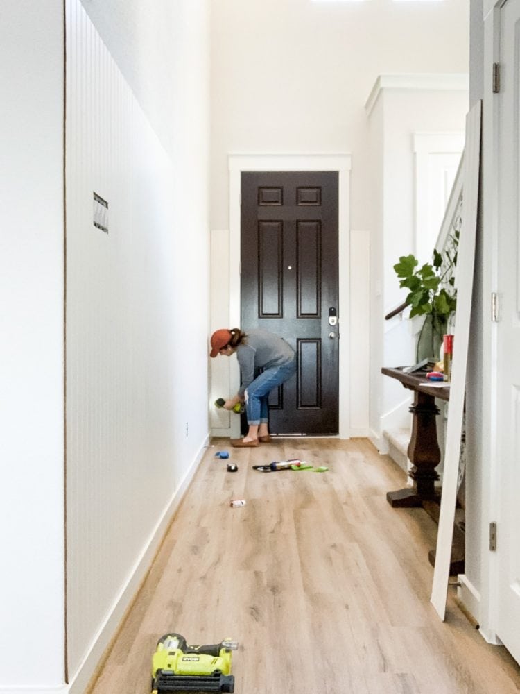 Woman using a nail gun to nail beadboard into wall