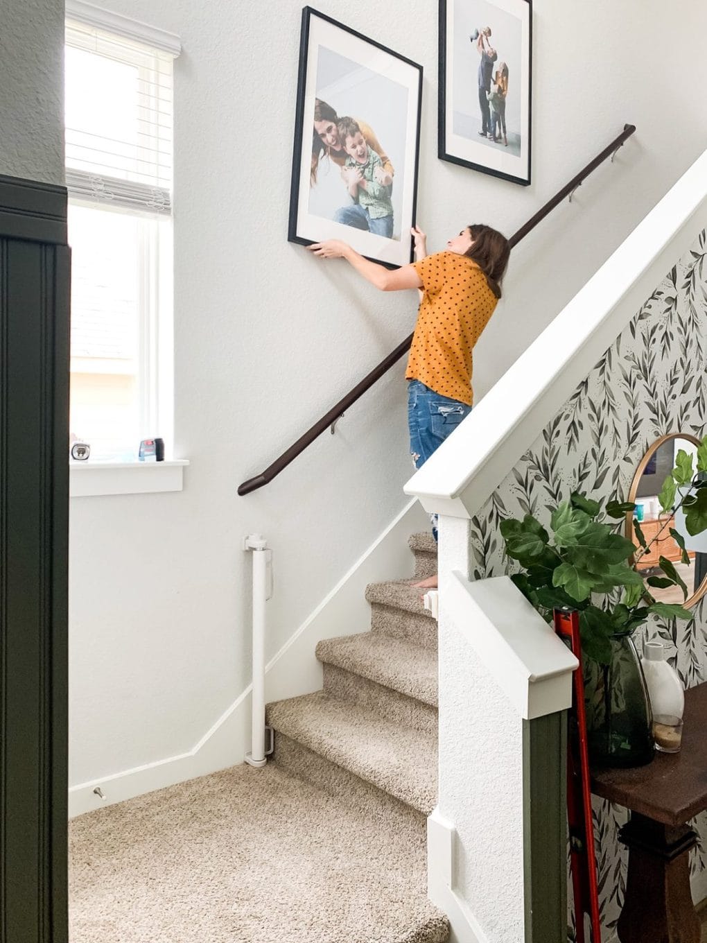 woman hanging a family photo on a staircase wall