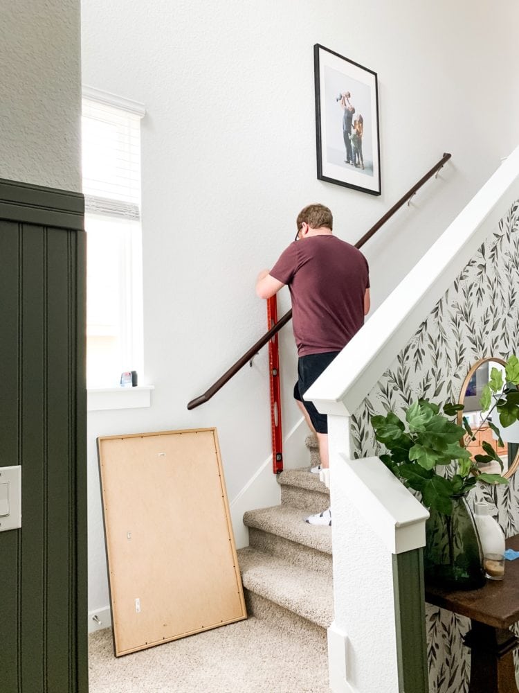 Man measuring to hang photos on a stairwell