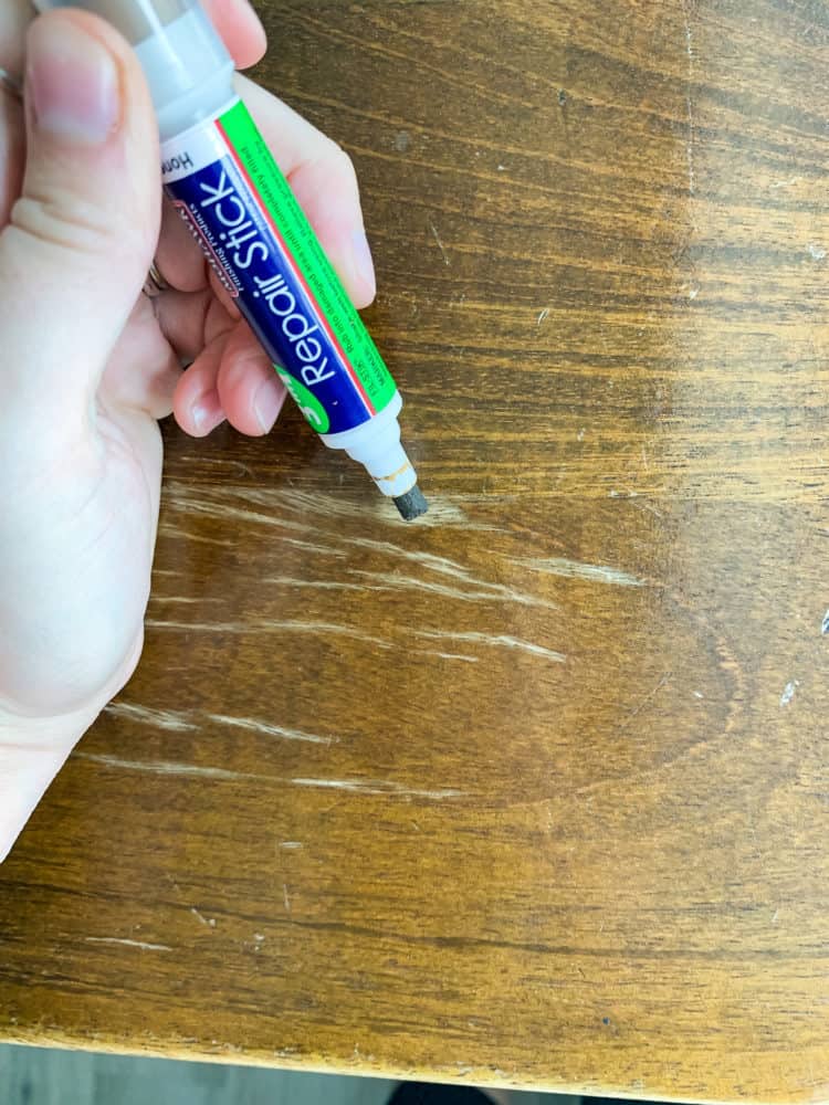 Close up of a hand using Mohawk's 3-in-1 repair stick on a dining table 