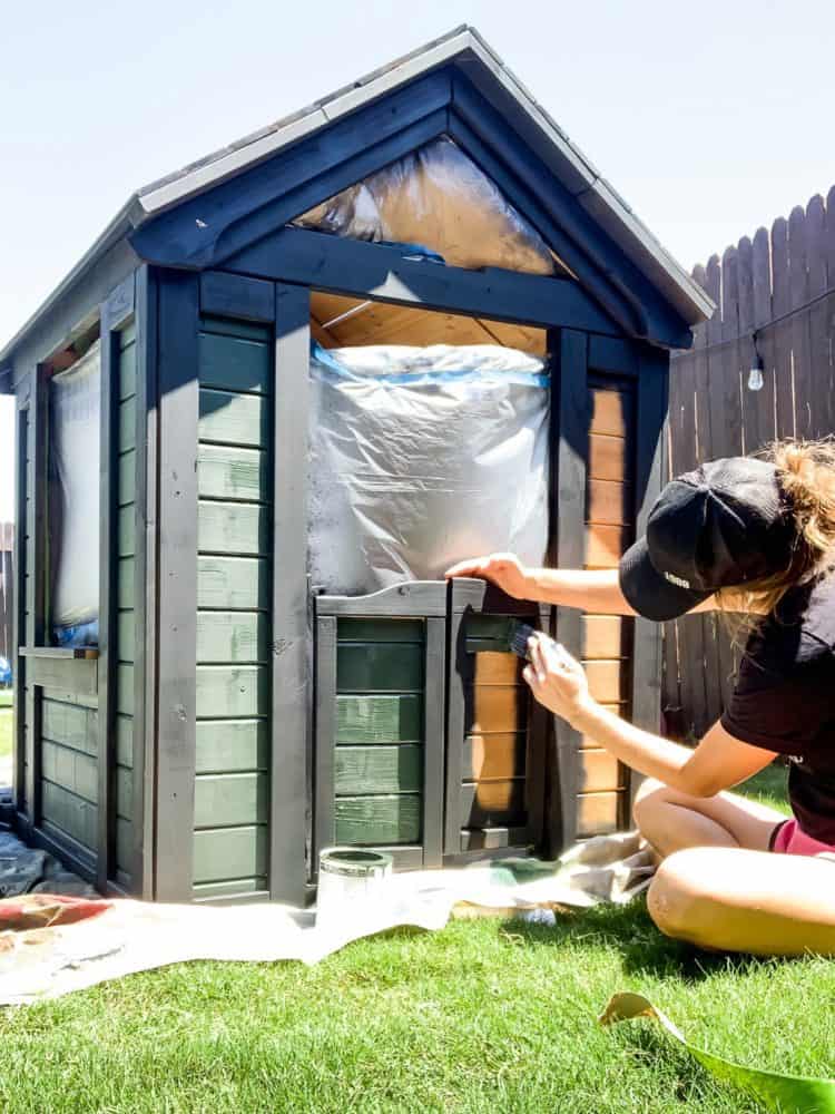 Woman painting a wooden playhous