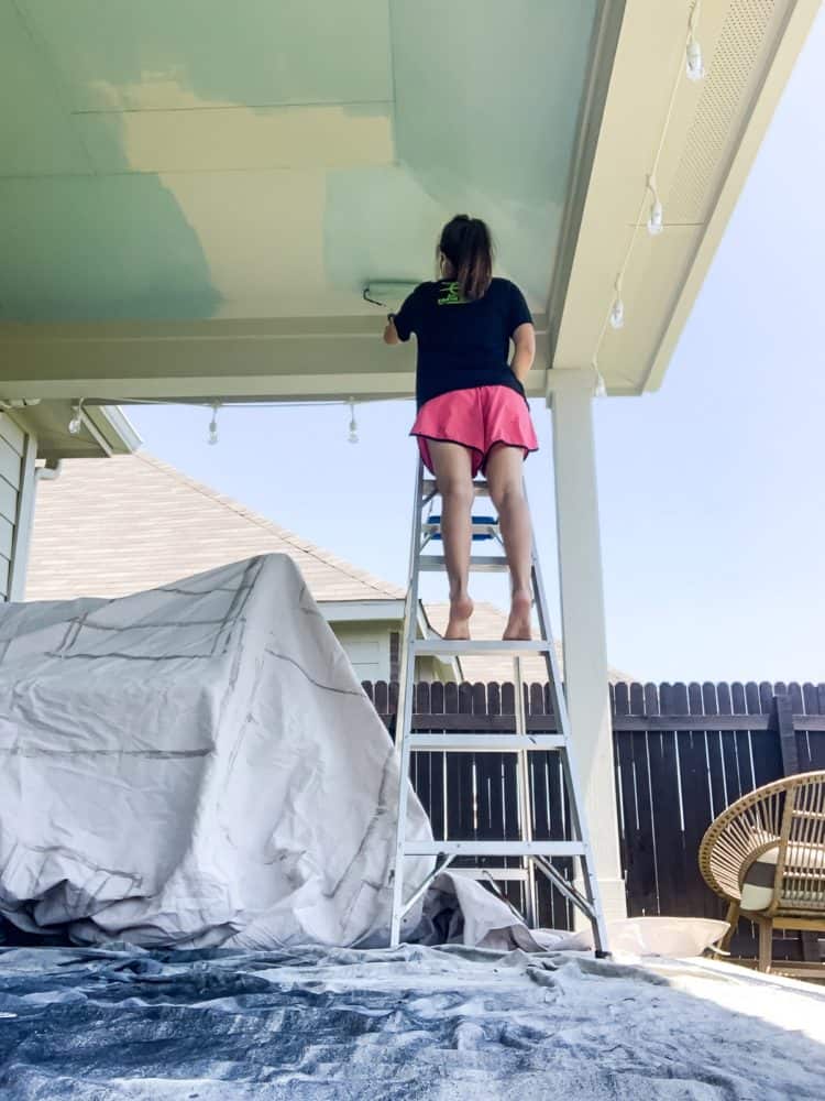 woman painting a back porch ceiling haint blue