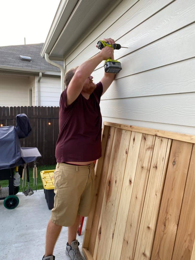 man hanging a large herb garden on wall
