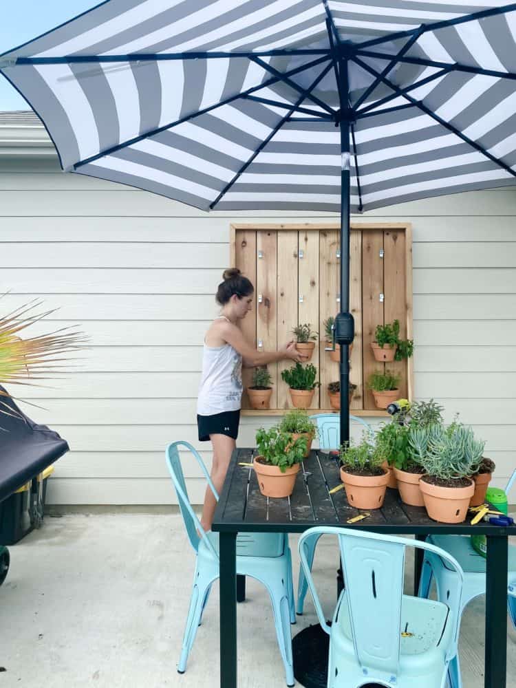 woman hanging plant on an herb garden