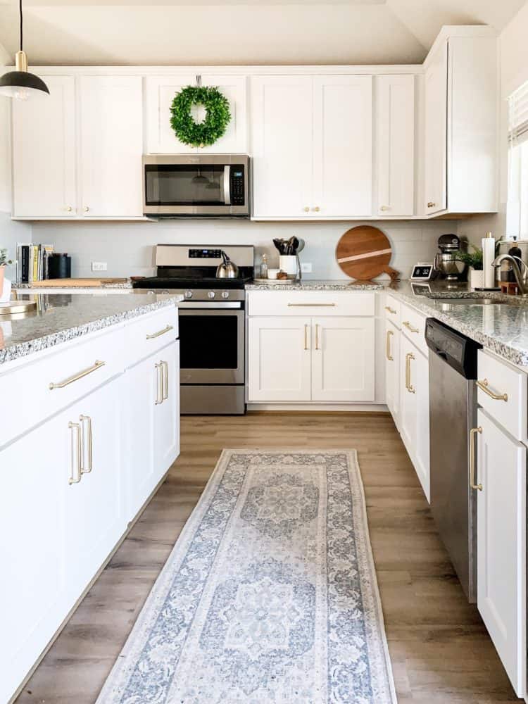 A white and gray kitchen with gold cabinet hardware 