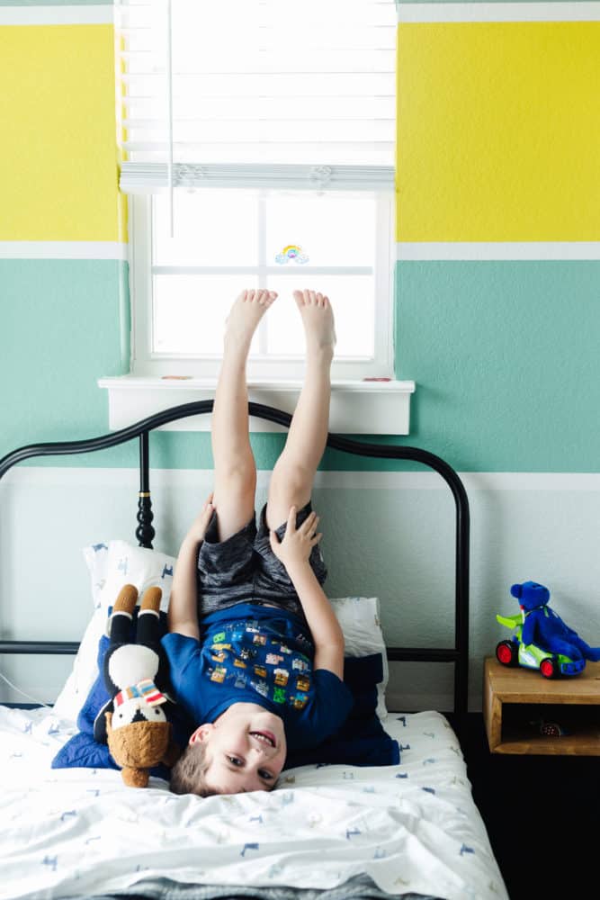 a young boy on a bed upside down and smiling