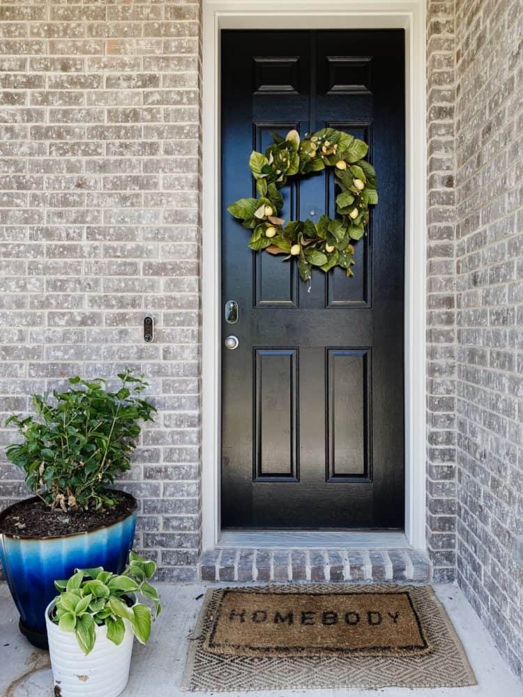 front porch with a faux wreath and potted plants 