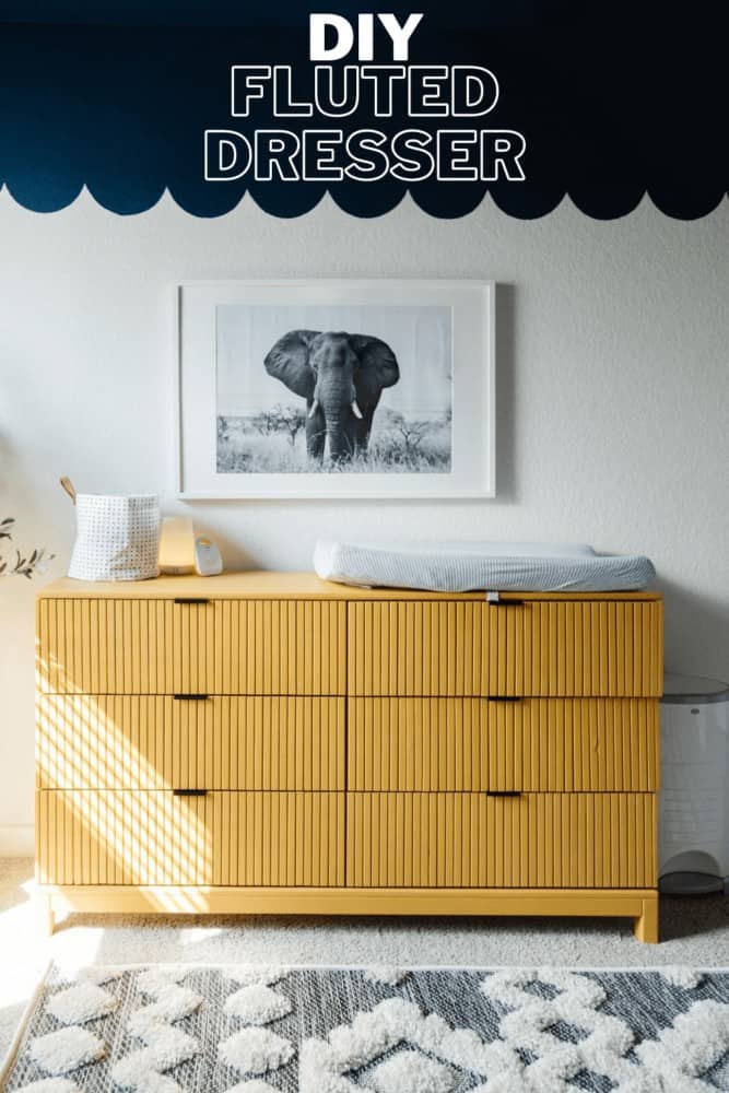 vertical image of an IKEA TARVA dresser that has had trim added to it and has been painted yellow. It's styled with an elephant art print above it and has a text overlay - diy fluted dresser