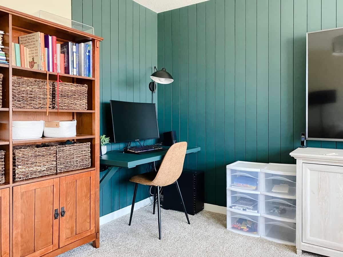 a corner of a living room with a desk and computer set up for virtual learning 