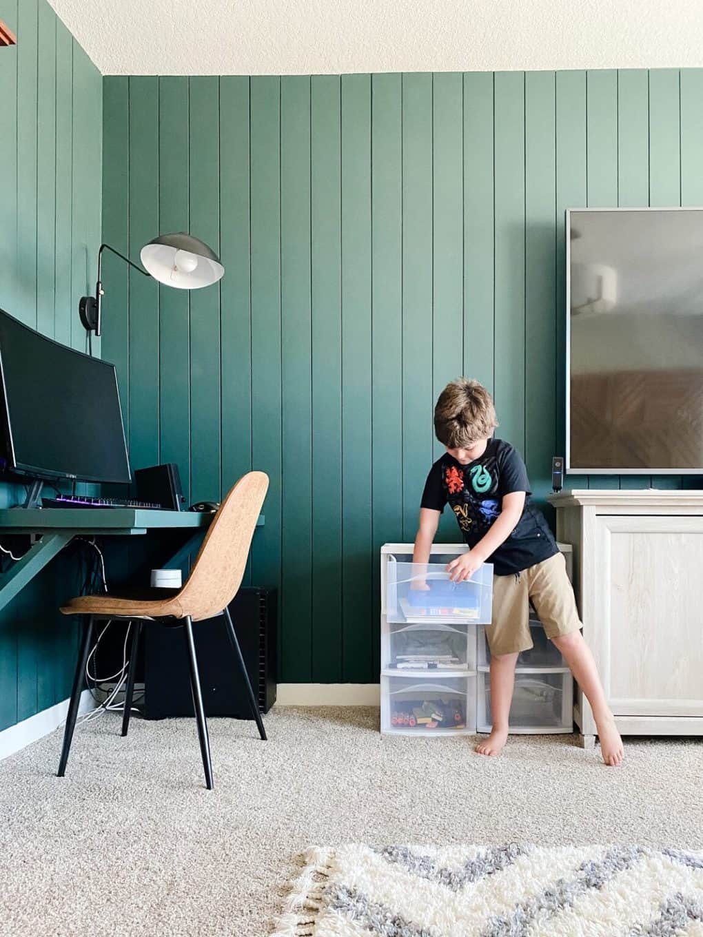 young boy grabbing school supplies from a set of plastic drawers 