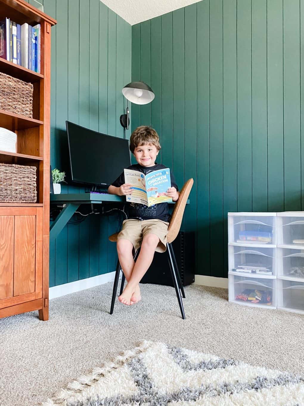 A young boy sitting at a corner work station with a book