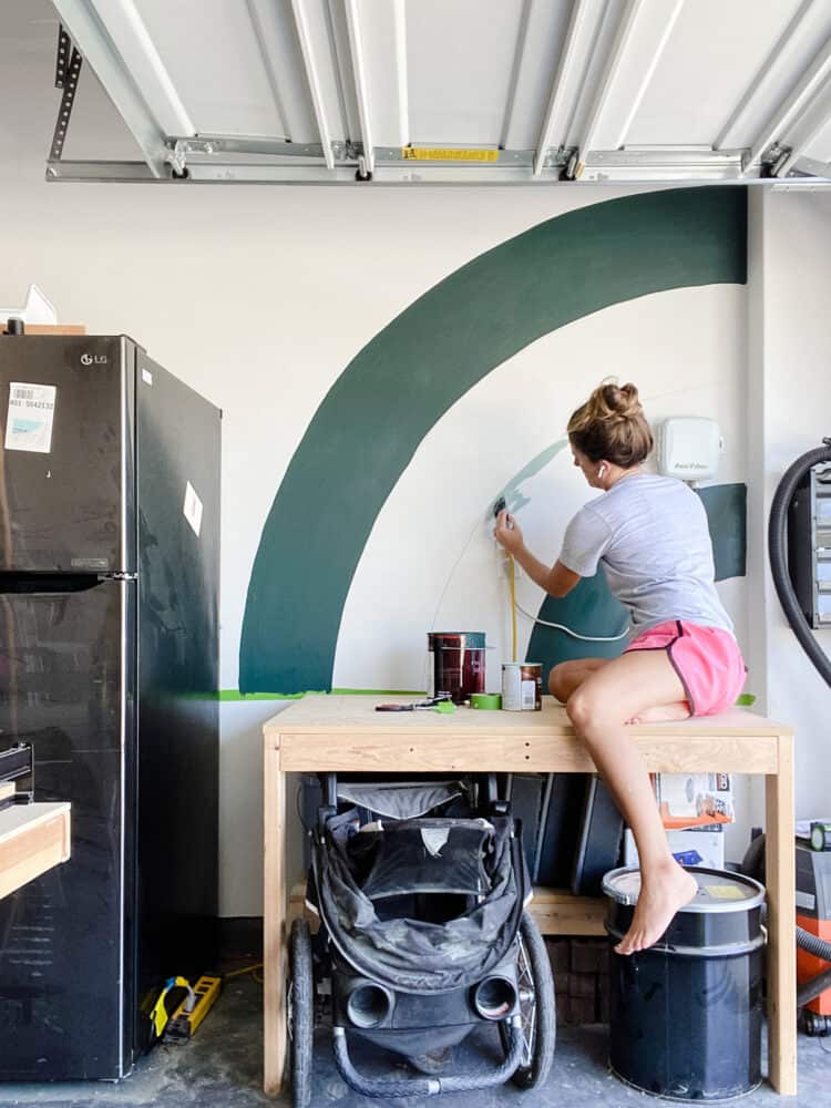 woman painting a mural on a garage wall