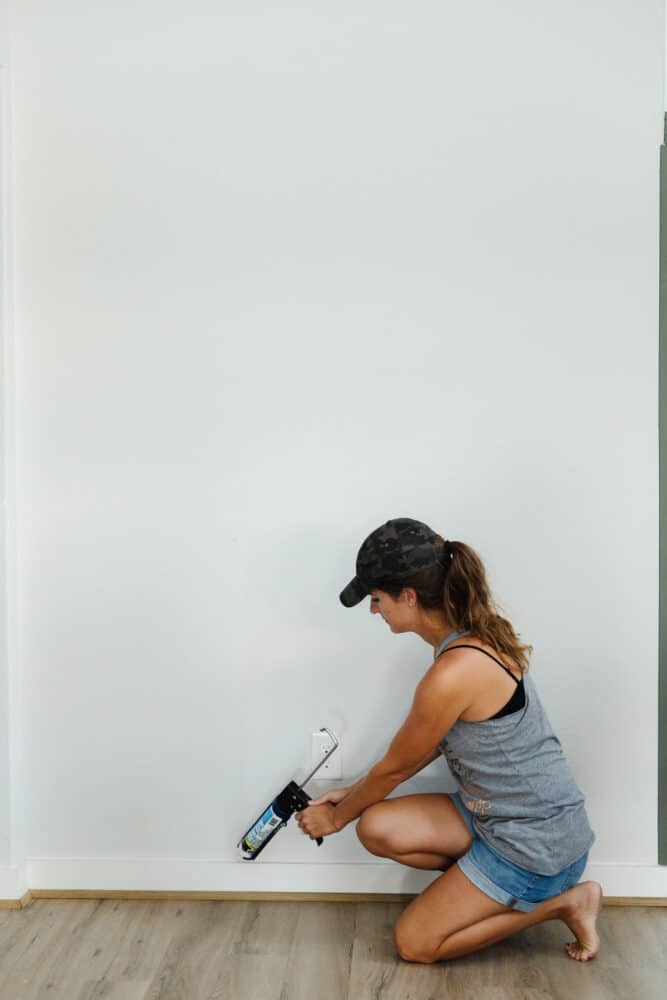 woman caulking a baseboard 