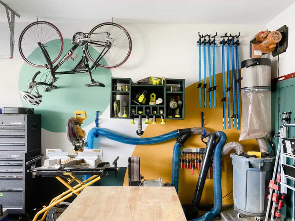 a garage with a colorful painted wall and tool storage 