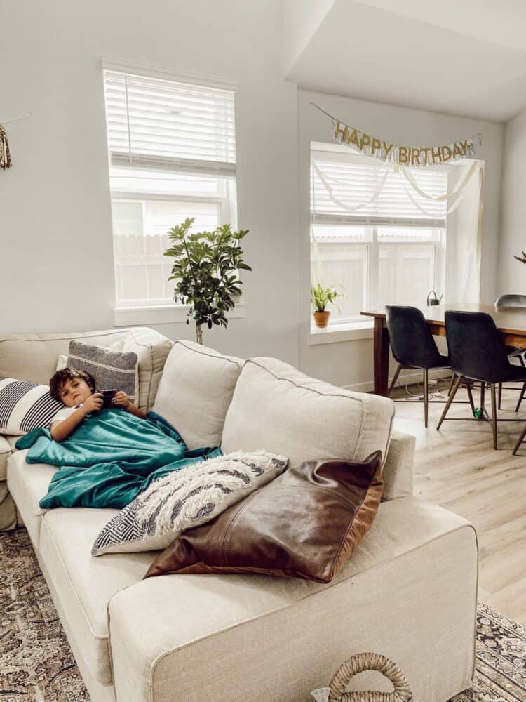 young child laying on a couch and using a weighted blanket 