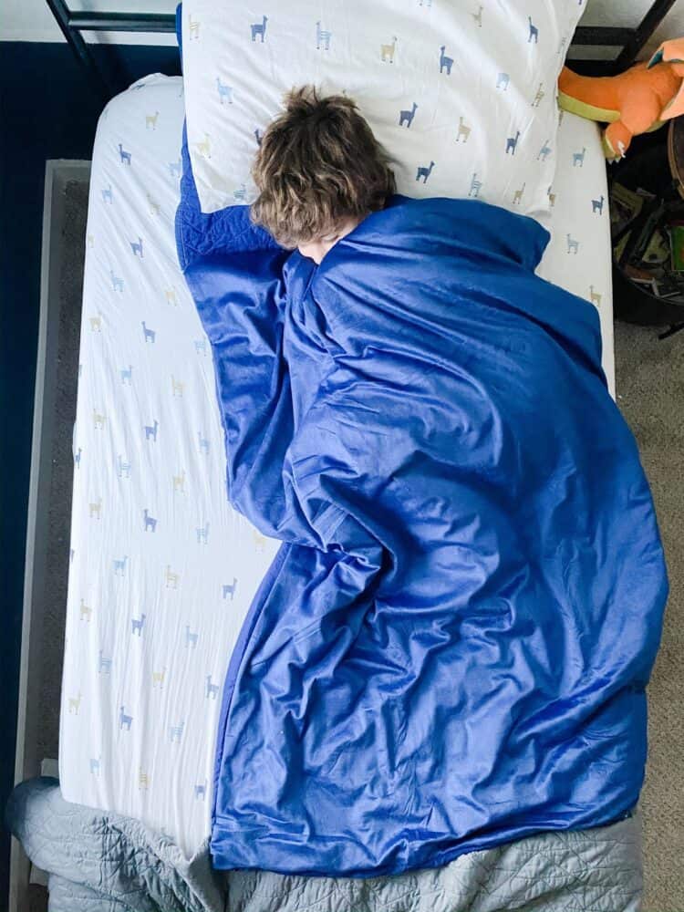 A young boy sleeping with a weighted blanket 