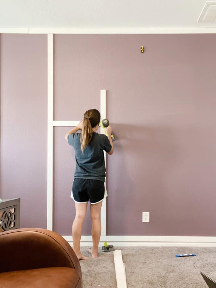 woman installing a DIY grid accent wall 