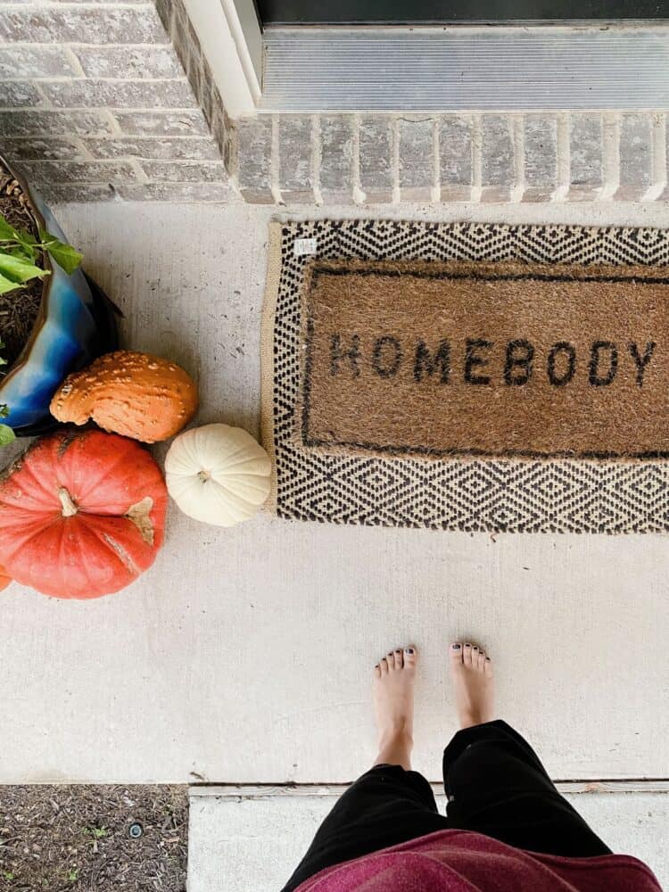 Overhead view of welcome mat and pumpkins