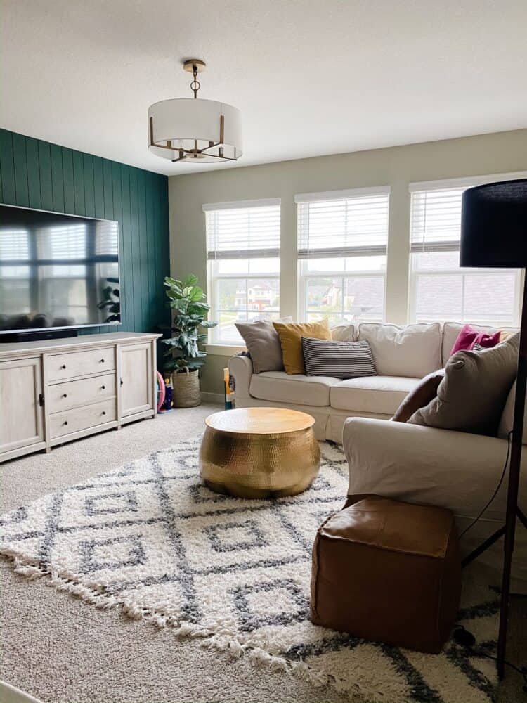 kid's game room with neutral furniture and a green accent wall 