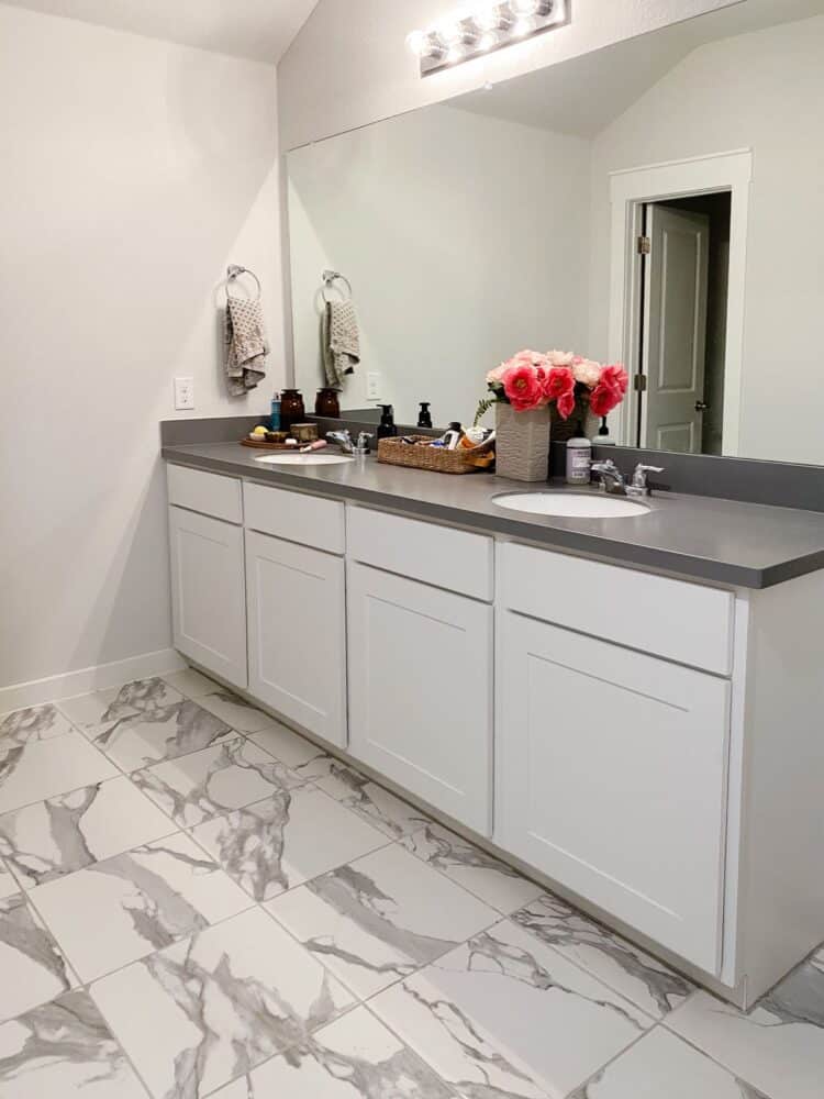 A gray and white master bathroom with an extra long vanity 
