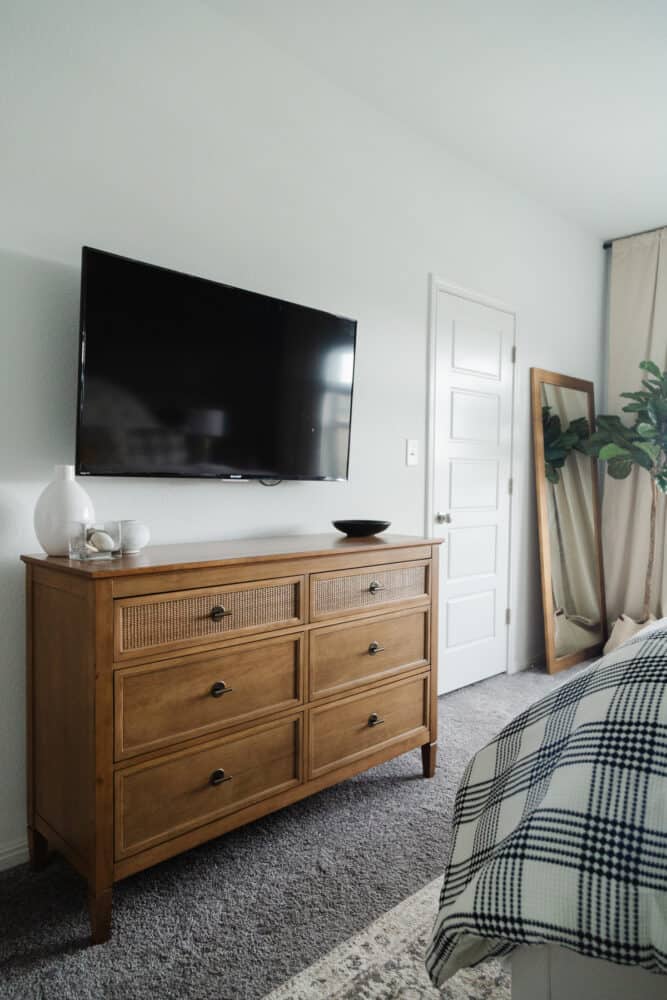 a white bedroom with a wooden dresser with cane accents 