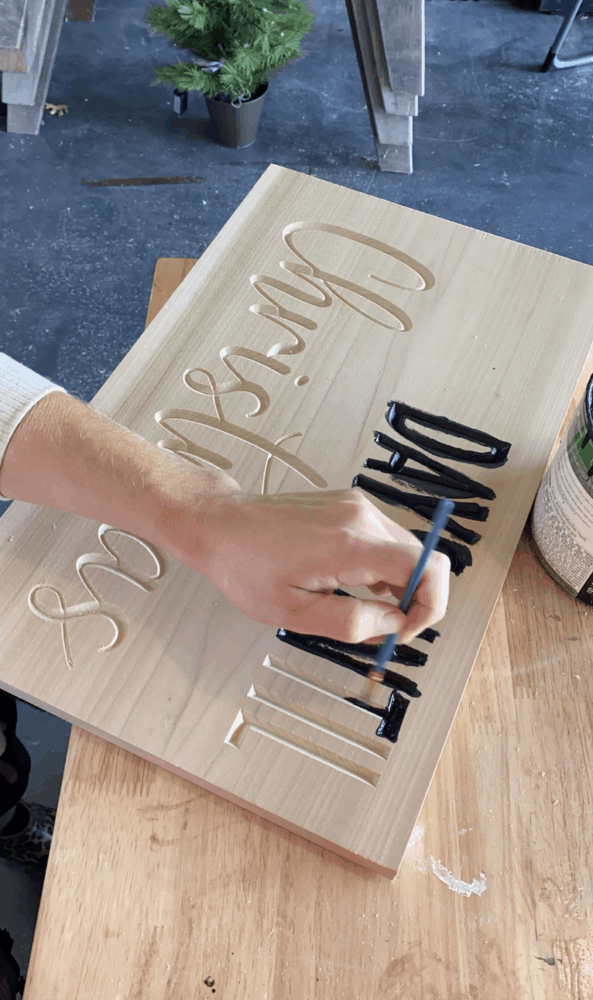 woman's hand painting a DIY carved wood Christmas countdown 