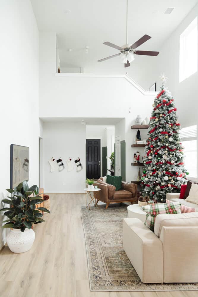 full view of cozy, neutral living room with a large Christmas tree 