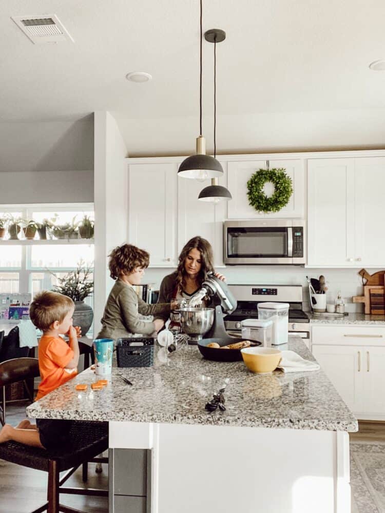 A mom and her children baking cookies in a white kitchen 