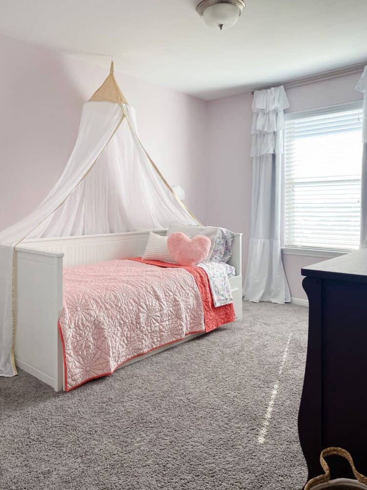 little girl's bedroom with princess canopy and rainbow mural